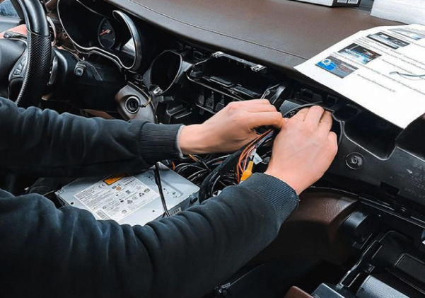 Мастер устанавливает автомагнитолу в штатное место
